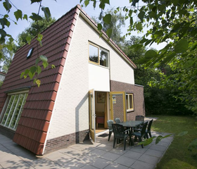 Een karakteristieke A-frame bungalow met een terras, gelegen in de groene en bosrijke omgeving van Bungalowpark Hoenderloo.