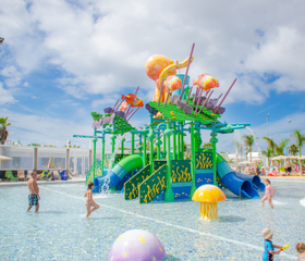Kinderen spelen in het kleurrijke waterspuitpark van Relaxia Lanzasur Club, met een grote octopus en kleine glijbaantjes.