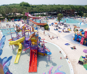 Overzicht van de kleurrijke waterspeeltuin in een van de aquaparken op Camping Union Lido, vol met glijbanen, speeltoestellen en spetterende kinderen.