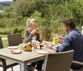 Een gezin geniet van een uitgebreid ontbijt aan de eettafel op het terras van hun cottage bij Center Parcs Park Bostalsee.