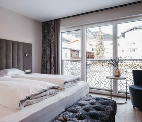 Tweepersoonsbed in hotelkamer met balkon met uitzicht over de sneeuw