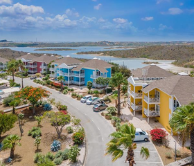 Luchtfoto van het kleurrijke CHOGOGO Dive & Beach Resort, met uitzicht op de zoutpannen van Jan Thiel baai op Curaçao.