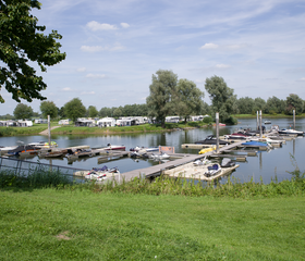 De jachthaven van Recreatiepark De Scherpenhof, met diverse boten aangemeerd in het water van de IJssel.