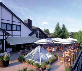 Het zonnige terras van het restaurant van Dorint Vakantiepark Daun, met uitzicht op de groene omgeving van de Eifel.