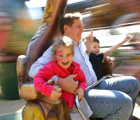 Een vader met zijn lachende kinderen in een snelle, draaiende attractie in attractiepark Europa-Park