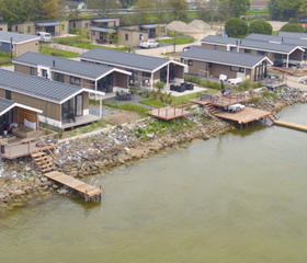 Luchtfoto van de moderne vakantiehuisjes met privé aanlegsteigers aan het water op EuroParcs Markermeer.
