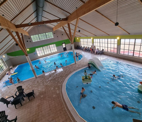 Overzicht van het overdekte zwemparadijs van EuroParcs Resort Limburg, met een recreatiebad, glijbaan en spelende gasten.