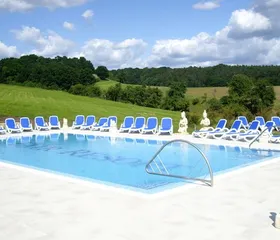 Het zonnige buitenzwembad van het FAIR Resort, omgeven door groene heuvels in de natuur van Thüringen.