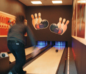 Een kind gooit een bowlingbal op de bowlingbaan van Ferienresort Bad Bentheim.