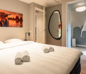 De comfortabele ouderslaapkamer met een opgemaakt tweepersoonsbed in de speciale Newborn boerderij op resort Hof van Saksen in Drenthe.