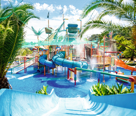 Groot waterspeelparadijs voor kinderen met glijbanen en een grote waterton in het waterpark van Hotel Aqualand Resort, Corfu.