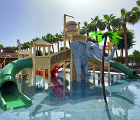Het spetterende kinderbad van Maspalomas Princess met een groene tunnelglijbaan en een grote, grijze olifant die water spuit.
