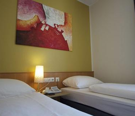 De netjes opgemaakte, comfortabele bedden in een hotelkamer van Hotel Winterberg Resort, klaar voor een goede nachtrust.