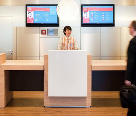 De moderne en vriendelijke receptie van het Ibis Hotel in Aken, waar gezinnen worden verwelkomd bij het inchecken.