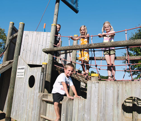 Kinderen klimmen en spelen op een groot houten piratenschip in de buitenspeeltuin van Eifelpark Kronenburger See.