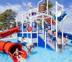 Kinderen spelen op een waterspeeltoestel met een rode glijbaan en sproeiers in het kinderbad van Zaton Holiday Resort, ideaal voor een gezinsvakantie.