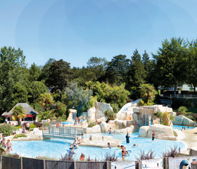 Het lagune zwembad in het buitenwaterpark van Domaine des Ormes, met rotsformaties, watervallen en veel zwemmende gezinnen op een zonnige dag.