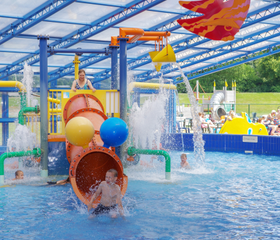 Jongen speelt in de waterspeeltuin met glijbaan en waterelementen in het openluchtzwembad op het kindvriendelijke vakantiepark Landal het Land van Bartje.