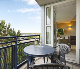 Balkon van een appartement bij Landal Ameland State met een zitje en prachtig uitzicht over de duinen en natuur van Ameland.