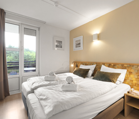 Comfortabele slaapkamer met een opgemaakt tweepersoonsbed en toegang tot het balkon in een appartement van Landal Ameland State.