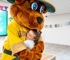 Klein meisje geeft een dikke knuffel aan Bollo de beer, de mascotte van Landal de Vers.