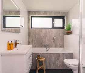 De moderne en lichte badkamer in een bungalow op Landal De Vlinderhoeve, uitgerust met een ligbad.