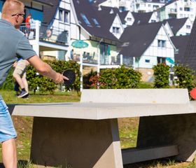Vader en zoon spelen een potje tafeltennis op een buitentafel op vakantiepark Landal Eifeler Tor.