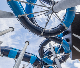 Van onderen gefotografeerd, de indrukwekkende blauw-zwarte constructie van de verschillende waterglijbanen tegen een blauwe lucht in het zwemparadijs van Landal Hof van Saksen.