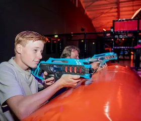 Twee jongens richten geconcentreerd hun lasergun op een doelwit in de spannende lasergame-arena van Landal Hoog Vaals.