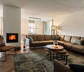 De sfeervolle en ruime woonkamer van een vakantiehuis op Landal Kaatsheuvel, met een grote hoekbank en een gezellige open haard.
