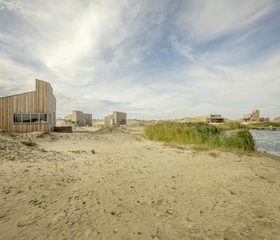 De duurzame, houten eilandhuisjes van Landal Marker Wadden, gelegen in het zand van het havenstrand aan de rand van het Markermeer.