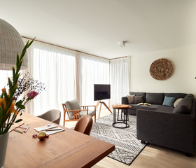 Stijlvol ingerichte woonkamer van een vakantievilla op Landal Puur Exloo, met een comfortabele zithoek en een ruime eettafel.