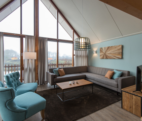 Het lichte en sfeervolle interieur van een waterwoning op Landal Reeuwijkse Plassen, met hoge ramen die een prachtig uitzicht bieden over het water.