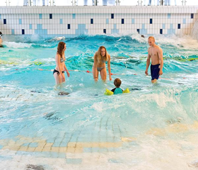 Een gezin met twee kinderen heeft plezier in het golfslagbad van het zwemparadijs bij Landal Salztal Paradies.