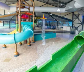 Het overdekte zwembad van Landal 't Loo met een groene glijbaan, een brede familieglijbaan en diverse waterspeeltoestellen.