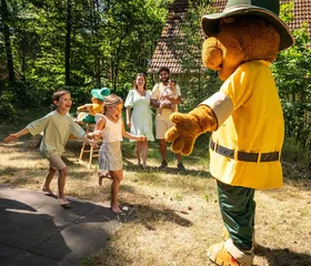 Enthousiaste kinderen begroeten en geven een high-five aan Bollo de Beer, de mascotte van Landal 't Loo.