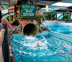 Kind maakt een 'Big Splash' aan het einde van de overdekte waterglijbaan in het zwembad van vakantiepark Landal Vennenbos in Noord-Brabant.