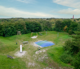 Luchtfoto van de speeltuin van Landal Vitamaris, met een airtrampoline en glijbaan, gelegen in een duinpannetje op Schiermonnikoog.