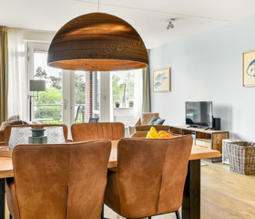 De sfeervolle eethoek in een appartement van Landal Vitamaris, met comfortabele leren stoelen rond een houten tafel.