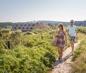 Koppel wandelt over een zandpad door het heuvelachtige duinlandschap op Vlieland, vlak bij Landal Vlieduyn.