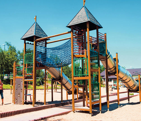 Het grote houten speelkasteel met torens, glijbanen en een klimnet in de buitenspeeltuin van vakantiepark Landal Warsberg.