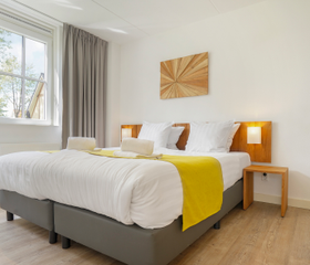Stijlvolle en lichte slaapkamer met een opgemaakt tweepersoonsbed in een vakantiehuis op Landal Waufsberg.