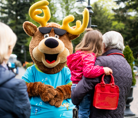 Parkmascotte Spot de eland poseert voor een foto met een meisje en haar opa en oma op Landgoed de Scheleberg.