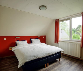 De ouderslaapkamer in een vakantiewoning op Landgoed Ruwinkel, met een netjes opgemaakt tweepersoonsbed.