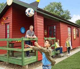 Een gezin dat aan het overgooien is met een bal voor hun rode vakantiehuisje in LEGOLAND Holiday Village.