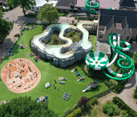 Luchtfoto van het grote buitenzwembad en waterpark van Marveld Recreatie met diverse waterglijbanen en een wildwaterbaan.