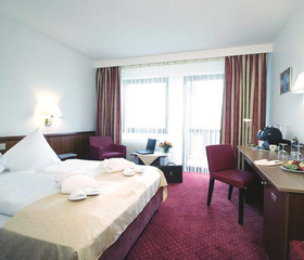 Een nette en comfortabele hotelkamer in het Mercure Hotel Bad Dürkheim, met een opgemaakt bed en een bureau, ideaal voor een gezin.