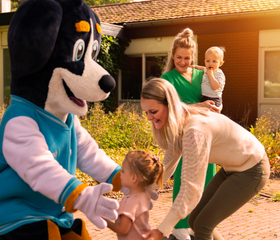 Mascotte Senn van Parc Heihaas begroet een gezin met jonge kinderen tijdens een meet & greet.