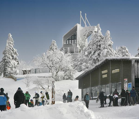 Het besneeuwde bergstation van de Wurmberg kabelbaan in Braunlage, met skiërs en wintersporters op de voorgrond.