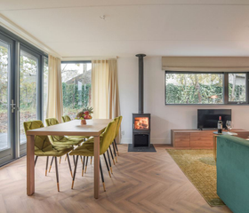 De lichte, moderne woonkamer met eethoek en gezellige houtkachel in een vakantiehuis op Residence Berger Duinen.